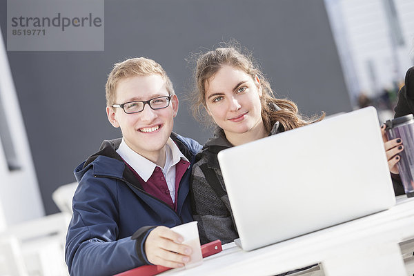 Zwei lächelnde Studenten mit Laptop im Freien  Portrait