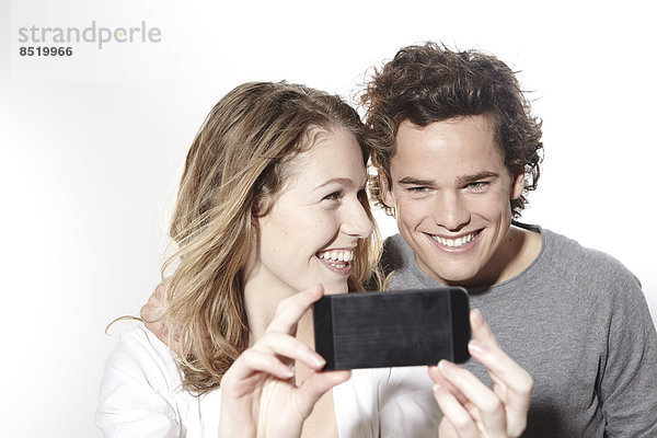Portrait eines glücklichen jungen Paares mit Smartphone  Studioaufnahme