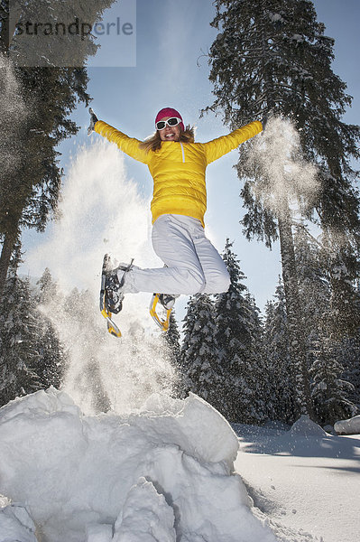 Austria  Salzburg State  Altenmarkt-Zauchensee  Woman with snowshoes jumping in winter landscape