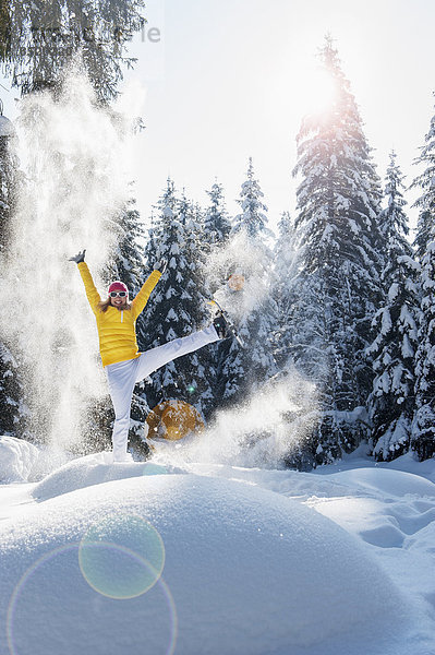 Österreich  Salzburger Land  Altenmarkt-Zauchensee  Frau mit Schneeschuhen springen in Winterlandschaft