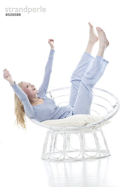 Blond young woman cheering in papasan chair