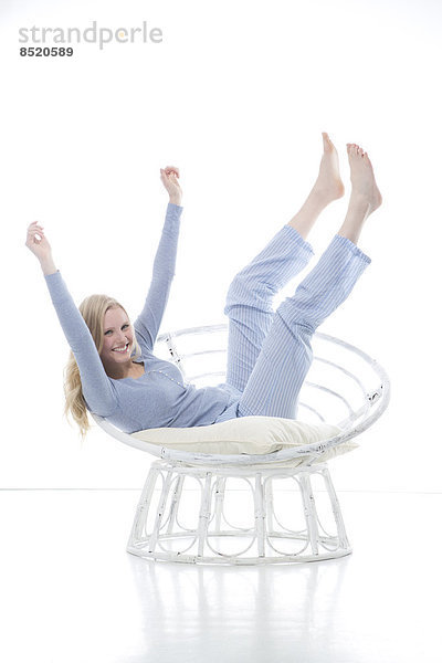 Blond young woman cheering in papasan chair