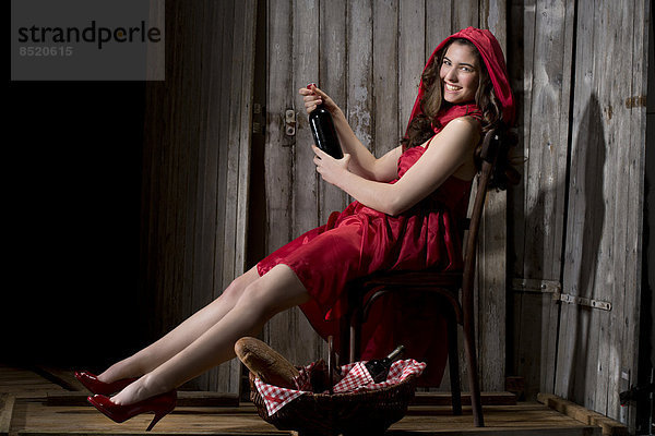 Young woman sitting in a shack dressed as Red Riding Hood  studio shot