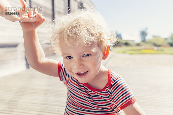 Porträt eines lächelnden Jungen mit dem Finger seiner Mutter