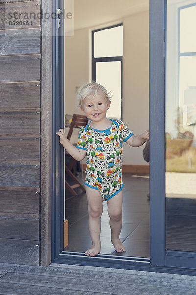 Lächelnder kleiner Junge an der Tür stehend