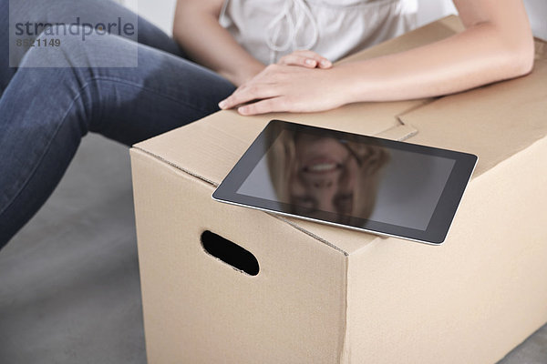 Young woman with cardboard box and tablet computer