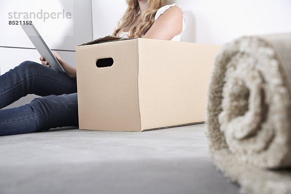 Young woman with cardboard box and tablet computer