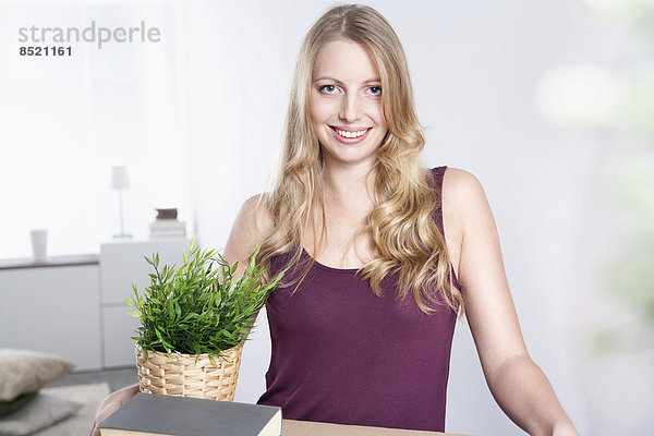 Smiling young woman carrying cardboard box