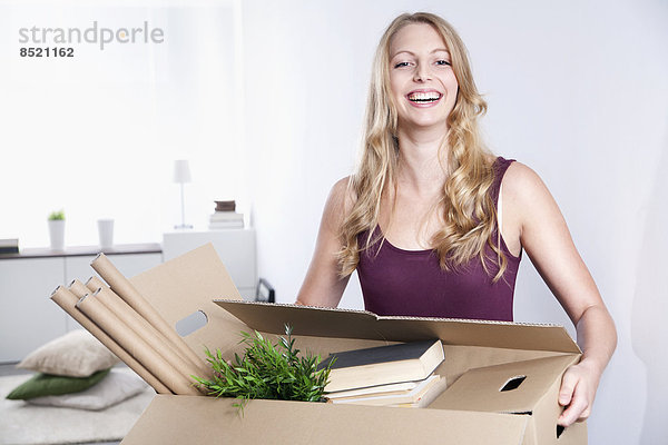 Smiling young woman carrying cardboard box