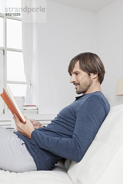 Man sitting on sofa  reading book