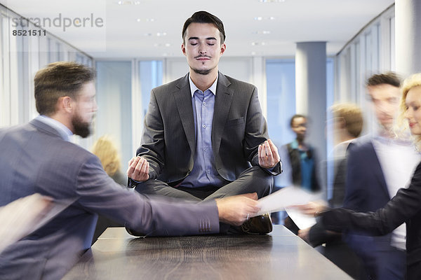 Geschäftsmann beim Meditieren auf dem Schreibtisch