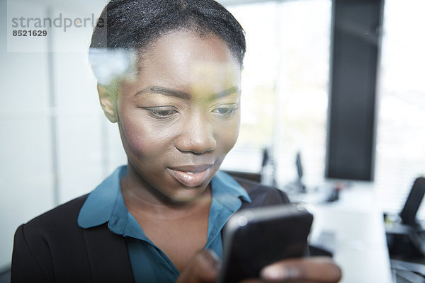Junge afro-europäische Geschäftsfrau mit Smartphone