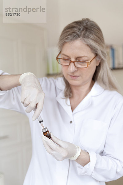Female alternatiße practitioner preparing injection syringe