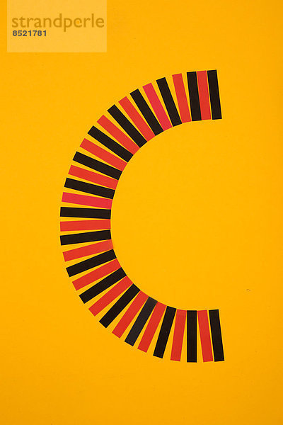 Buchstabe ''C'' aus roten und schwarzen Papierstreifen auf gelbem Hintergrund  Studioaufnahme'.