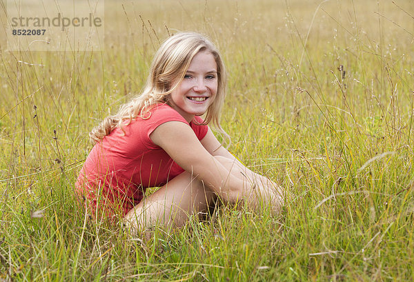 Austria  Salzkammergut  Mondsee  young woman sitting in a meadow