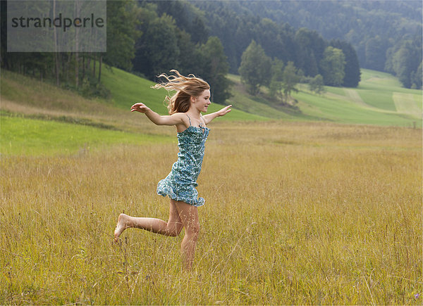 Österreich  Salzkammergut  Mondsee  junge Frau auf einer Wiese laufend