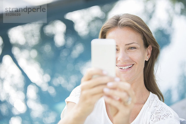 Frau mit Handy am Pool