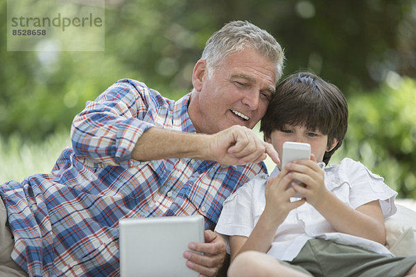 Großvater und Enkel mit digitalem Tablett und Handy