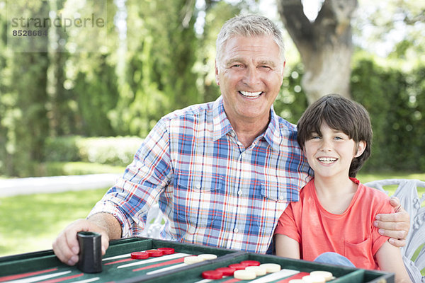 Großvater und Enkel spielen Backgammon auf der Terrasse