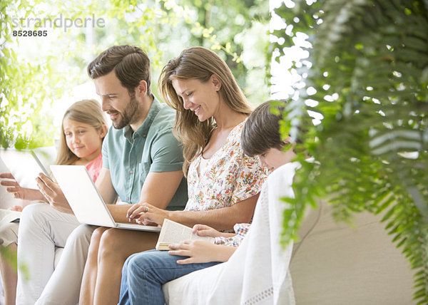 Familie lesen und Technik auf der Terrasse nutzen