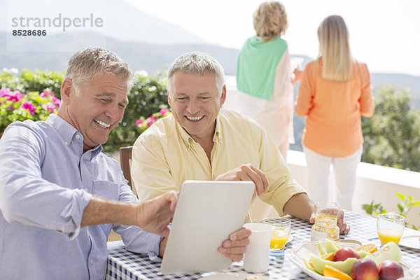 Senioren mit digitalem Tablett am Terrassentisch