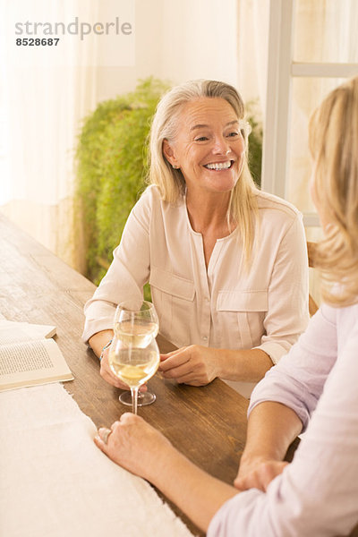 Seniorinnen trinken Weißwein am Esstisch