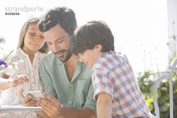 Vater und Kinder mit dem Handy im Freien