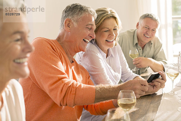 Seniorenpaare trinken Wein und schauen auf das Handy