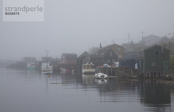 Nebel umgebende Häuser und Boote auf dem Fluss