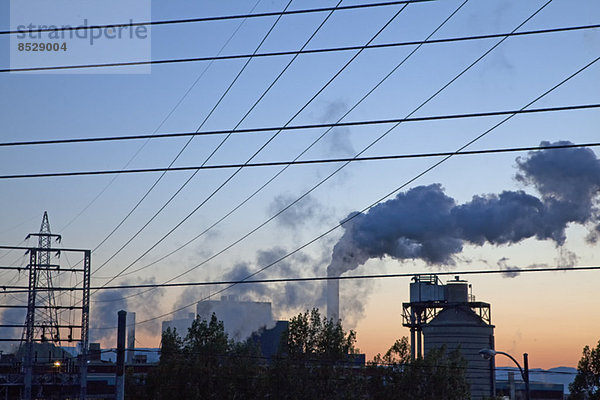 Silhouette des Rauchs  der bei Sonnenaufgang aus der Fabrik austritt.