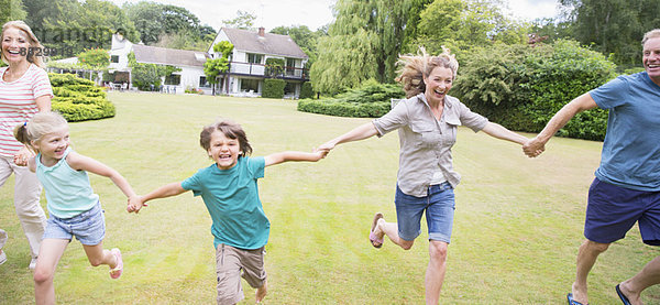 Mehrgenerationen-Familie beim Händchenhalten und Laufen im Hinterhof