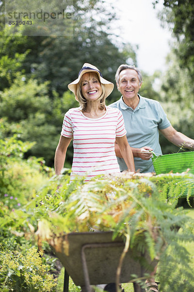 Seniorenpaar mit Schubkarre und Eimer im Garten