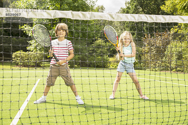 Kinder spielen Tennis auf dem Rasenplatz