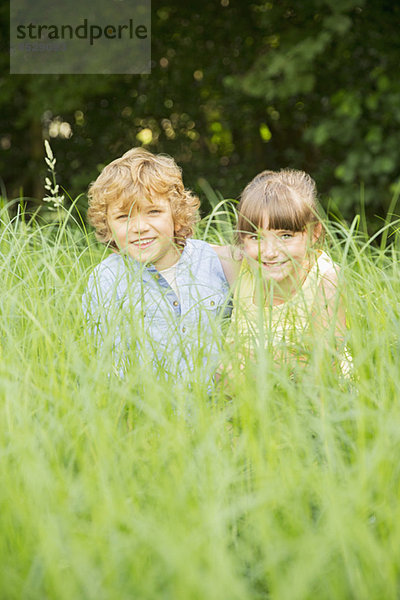 Kinder spielen im hohen Gras