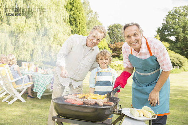 Mehrgenerationen-Männer beim Grillen von Fleisch und Mais im Hinterhof