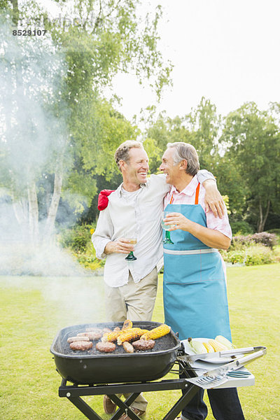 Männer umarmen sich beim Grillen im Garten