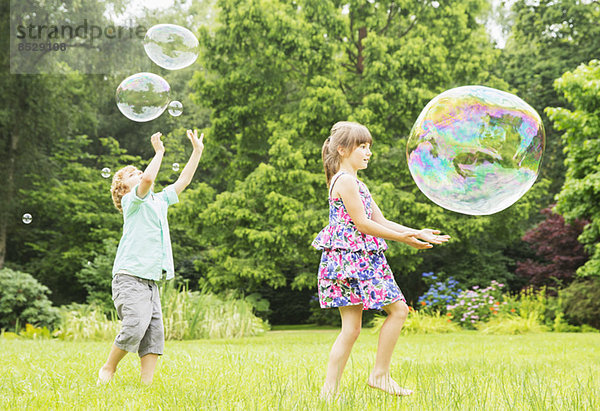 Kinder spielen mit Blasen im Freien