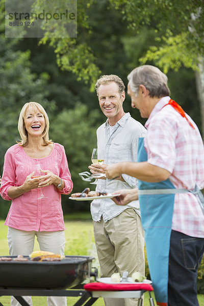 Familie steht beim Grillen im Garten