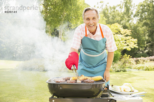 Mann beim Grillen auf dem Grill im Garten