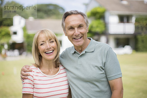 Lächelndes Seniorenpaar umarmt sich im Freien