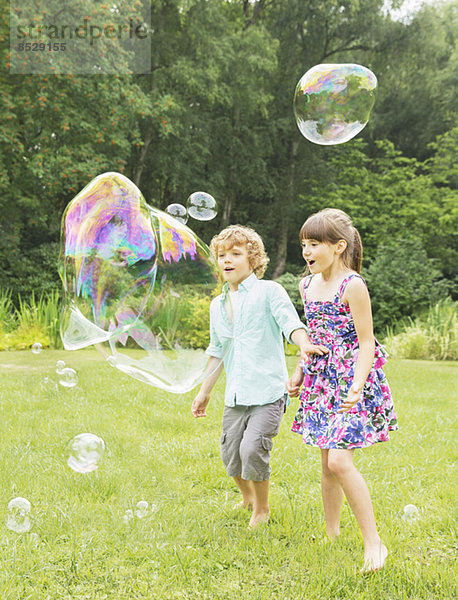 Kinder spielen mit Blasen im Garten