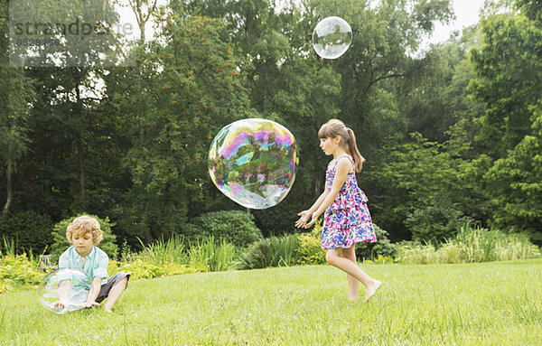Kinder spielen mit Blasen im Garten