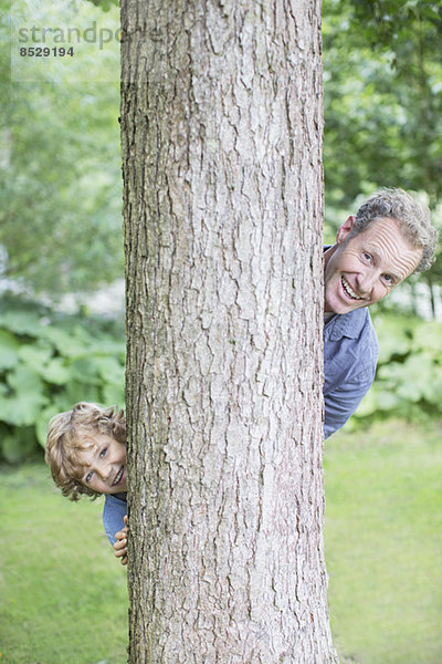 Vater und Sohn schauen von hinten auf den Baum.