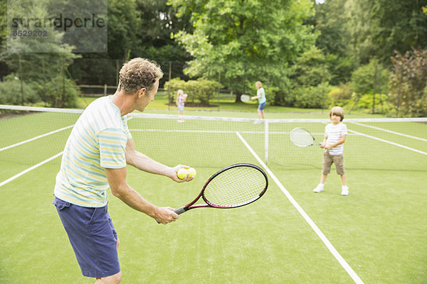 Familie spielt Tennis auf dem Rasenplatz