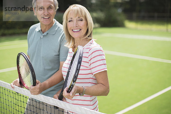 Paar lächelt auf dem Tennisplatz