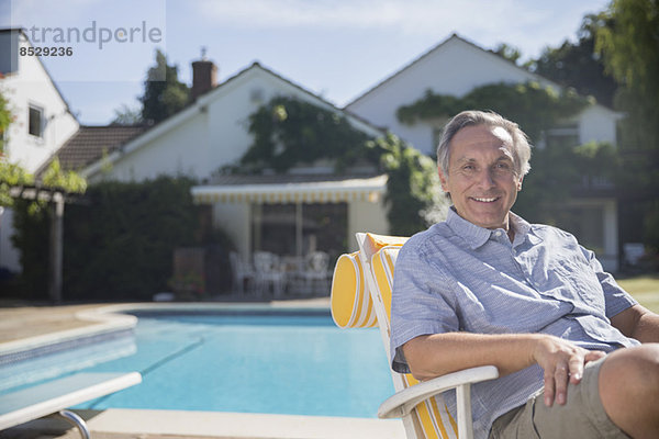 Lächelnder Mann im Loungesessel am Pool