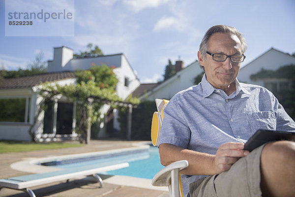 Mann mit digitalem Tablett am Pool