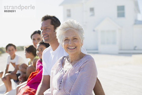 Mehrgenerationen-Familie lächelt vor dem Strandhaus