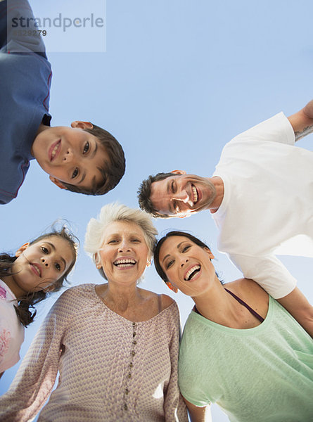 Mehrgenerationen-Familie lächelt vor blauem Himmel