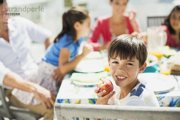 Junge isst Obst mit Familie am Tisch auf der Sonnenterrasse